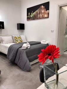 a bedroom with a large bed and a red flower at Alle porte del Castello 23 in Catania