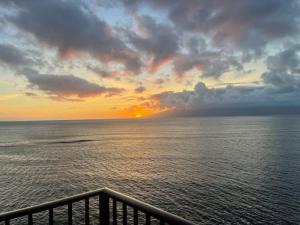 a sunset over the ocean with the sun setting at Unforgettable Oceanfront Stay , Nature, Luxury & Tranquility in Kahana +44 photos