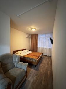 a bedroom with a bed and a couch and a window at Кемпинг Мечта in Uralsk