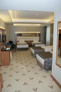 a hotel room with three beds and a desk at Carmine Otel in Kırıkkale