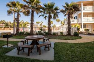 a picnic table and chairs in a park with palm trees at Across the Street from beach with 2 pools in Panama City Beach +6 photos