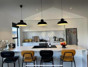 弗兰克顿Modern home with SPA的厨房设有小岛,配有酒吧椅和灯