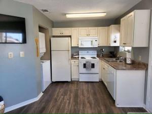 a kitchen with white appliances and white cabinets at Across the Street from beach with 2 pools in Panama City Beach