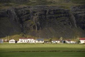 a field with houses and a mountain in the background at Berunes HI Hostel in Berunes