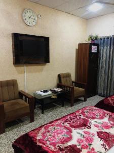 カラチにあるKarachi Airport Guest Houseのベッド1台、椅子2脚、テレビが備わる客室です。