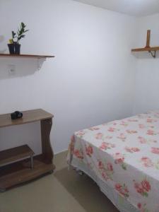 um quarto com uma cama e uma mesa de madeira em Kitnet na praia da Macumba no morro do Rangel no Rio de Janeiro