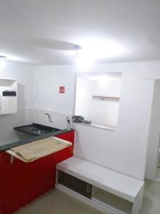 uma cozinha com um lavatório e um armário vermelho em Kitnet na praia da Macumba no morro do Rangel no Rio de Janeiro