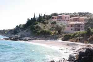 a beach with houses on a hill next to the water at Anassa Mare Villas & Residences in Gaios