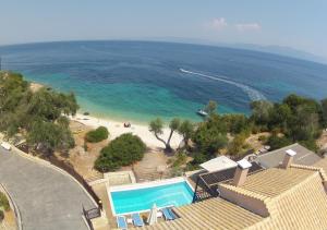 a house with a swimming pool next to a beach at Anassa Mare Villas & Residences in Gaios