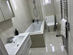 a white bathroom with a sink and a tub and a toilet at Spectacular London Stay in Crystal Palace