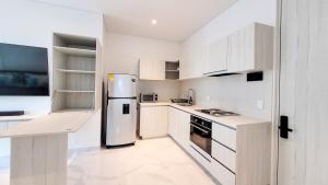 eine Küche mit weißen Schränken und einem Edelstahlkühlschrank in der Unterkunft PLAYA BELLO HORIZONTE "Encanto exclusivo a pasos del Mar" in Playa Bello Horizonte