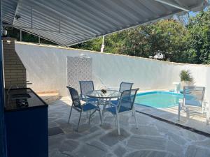a patio with a table and chairs next to a pool at Pousada Villa Margarida in Búzios
