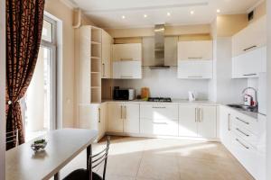 a kitchen with white cabinets and a table at HomeService Apartments on Stefan cel Mare boulevard in Chişinău