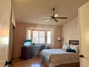 a bedroom with a bed with a ceiling fan and a desk at Western Horizon Home in Hemet +60 photos