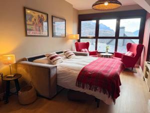 a bedroom with a large bed with two red chairs at Apartamento Vistas Peña Telera con WIFI in Panticosa