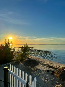 a white fence on the beach with the sunset at Ocean Depth Room at Barnacle Resort in Big Pine Key +30 photos