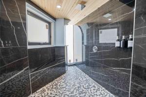 a bathroom with a shower with black marble tiles at Ocean Depth Room at Barnacle Resort in Big Pine Key