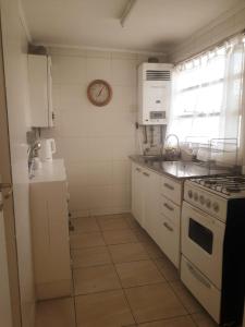 a kitchen with white appliances and a clock on the wall at Cuatro Estaciones in San Carlos de Bariloche +1 photo