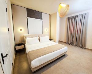 Un dormitorio con una gran cama blanca con una gran ventana. en Elite Residence, en Accra