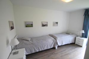 ein weißes Schlafzimmer mit 2 Betten und einem Schreibtisch mit einer Lampe in der Unterkunft 1902 - Am Kurpark in Dahme