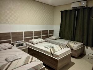 Habitación con 3 camas y cortinas. en Hotel motel Raiar do Sol santo Amaro, en São Paulo