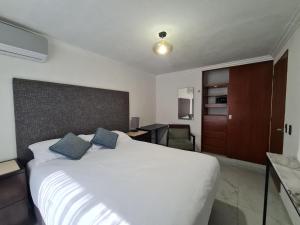 a bedroom with a large white bed with blue pillows at ALOJAMIENTO CeNTRICO CANCuN in Cancún