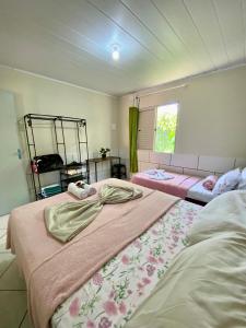 a bedroom with two beds and a window at Casa acolhedora ideal para famílias, com Wi-Fi rápido, cozinha exclusiva e equipada, varanda com churrasqueira - A apenas 1 km da praia do bairro e 5 km da charmosa Praia da Vila in Imbituba