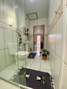 a bathroom with a toilet and a glass wall at Casa acolhedora ideal para famílias, com Wi-Fi rápido, cozinha exclusiva e equipada, varanda com churrasqueira - A apenas 1 km da praia do bairro e 5 km da charmosa Praia da Vila in Imbituba +44 photos