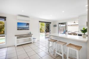 una cocina con encimera blanca y taburetes en Seatides Mooloolaba, en Mooloolaba