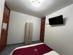 a bedroom with a refrigerator and a tv on the wall at HOTEL AREQUIPA in Nazca