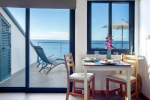 Un comedor con mesa y sillas en un balcón. en The Wave House - Oceanfront, en Jardim do Mar