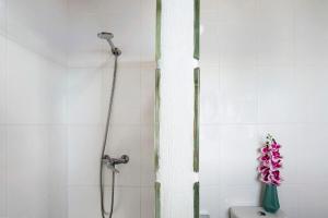 y baño con ducha y jarrón de flores. en The Wave House - Oceanfront, en Jardim do Mar