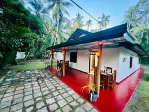 una pequeña casa con un exterior rojo y blanco en Lagoon House - Hiriketiya, en Dikwella