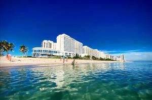 two people standing in the water on a beach with buildings at Luxury - Ocean front - 3 Bedroom 2 Bathroom - Penthouse in Miami Beach