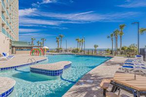 a swimming pool with chairs and a playground at Seas The Day - Stunning Ocean Views, Direct Beach Access, Prime Location! in Myrtle Beach