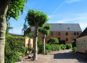 un vieux bâtiment en briques avec un arbre devant lui dans l'établissement Andelen Guesthouse, à Ærøskøbing