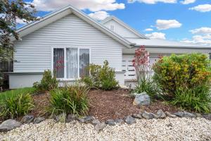 a white house with flowers in the front yard at Tea Tree Retreat - 5 Bedrooms, sleeps 13 in Inverloch