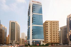 un grand bâtiment dans une ville avec de grands bâtiments dans l'établissement Ramada Abu Dhabi Corniche, à Abu Dhabi