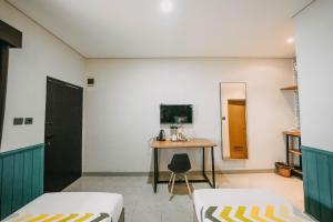 a room with two beds and a desk and a tv at Handayani Hotel in Sumedang Utara
