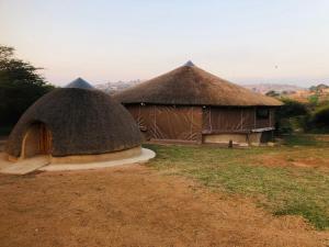 2 cabanes au toit de chaume dans un champ dans l'établissement Indlondlo Cultural Village, à Cato Ridge