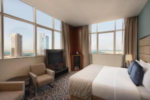 a hotel room with two beds and a television at Ramada Abu Dhabi Corniche in Abu Dhabi
