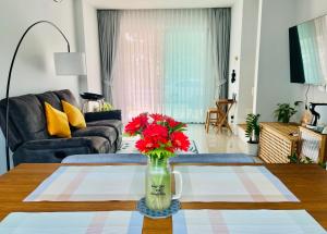 a living room with a vase with red flowers on a table at Borbaimai home in Chiang Rai