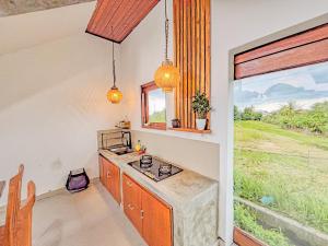 a kitchen with a counter with a microwave and a window at Rama Guesthouse in Tanah Lot