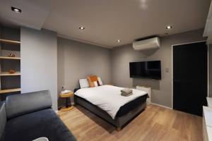 a bedroom with a bed and a couch and a television at Real Life IIDABASHI in Tokyo