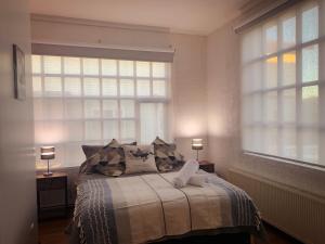 a bedroom with a bed with two windows at Patagonia Heritage Home in Punta Arenas