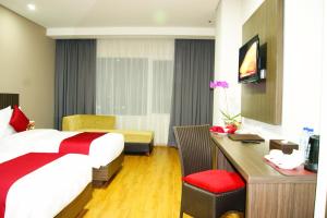 una camera d'albergo con letto e scrivania di Merapi Merbabu Hotels Bekasi a Bekasi