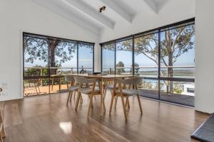 Un comedor con mesa y sillas y grandes ventanales. en Woolpack Inn - Merimbula, en Merimbula