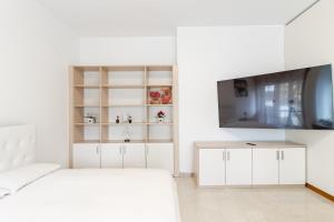 Un dormitorio blanco con una cama y un televisor. en Moncler House Navigli, en Milán