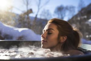 a woman is in a hot tub with snow at Das Landhaus Oberstdorf in Oberstdorf