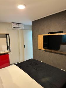 a hotel room with a bed and a flat screen tv at O EDIFÍCIO é de frente ao MAR de Pajuçara NEO 2 Qts 2gar - Adm Nutelss in Maceió
